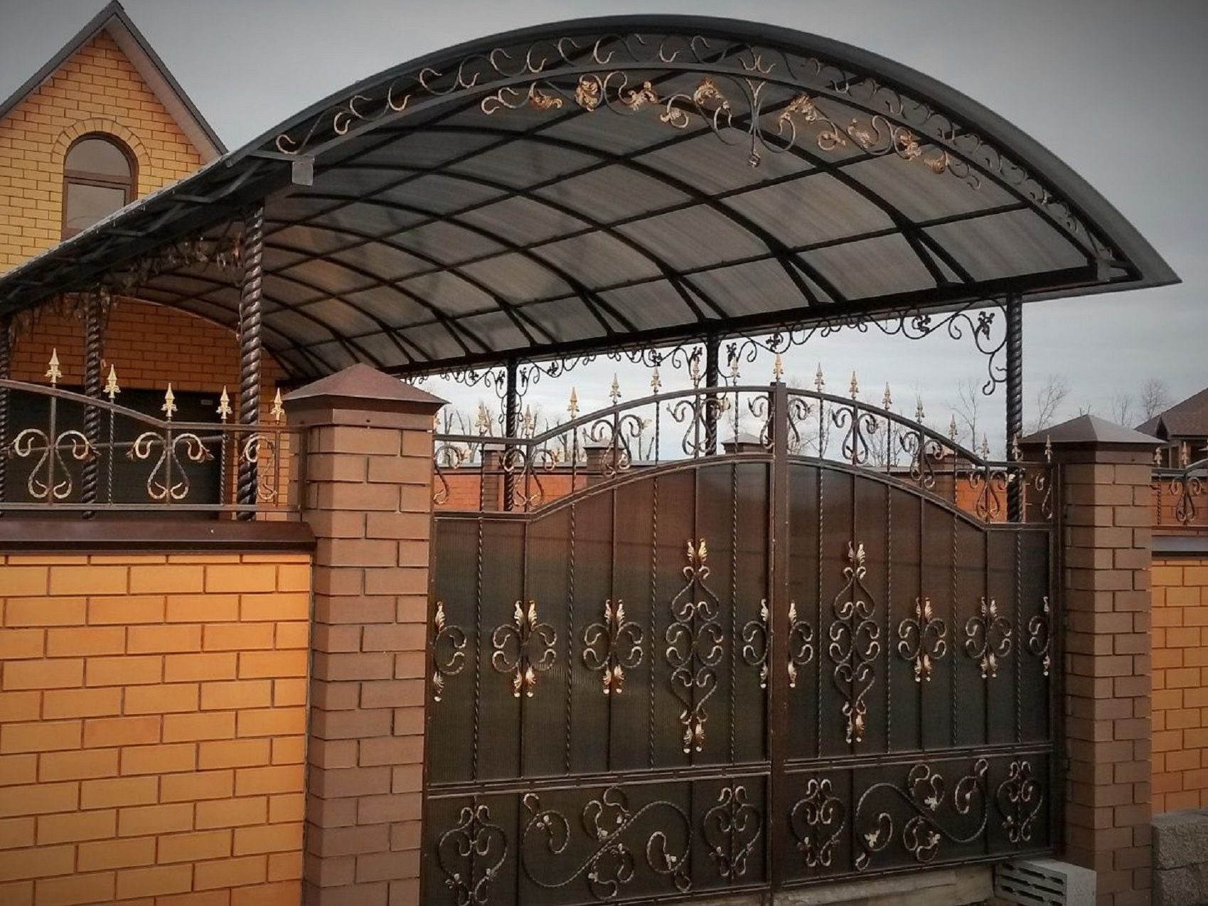 Арочный навес с коваными элементами над въездными воротами